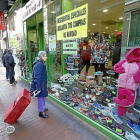 Una mujer con un carrito de compra observa las ofertas de un escaparate en la calle Teresa Gil.-J.M.LOSTAU
