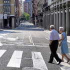 Dos ancianos cruzan una céntrica calle sin coches en la calzada.-MIGUEL ÁNGEL SANTOS