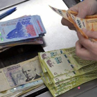 Un cajero cuenta billetes de pesos en un supermercado de Buenos Aires, el pasado jueves.-JUAN MABROMATA (AFP)