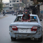 Un niño sirio sentado sobre un coche dañado por las explosiones del este de Ghouta.-AMER ALMOHIBANY