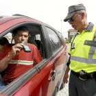 Un conductor realiza la prueba de alcoholemia ante la mirada de un agente de la Guardia Civil.-ICAL
