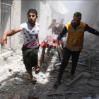 Dos hombres evacúan a una persona víctima de los bombardeos de hoy en el barrio de Al Qatarji de Alepo.-AFP / AMEER ALHALBI