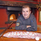 Sergio Blázquez, junto a la boca del horno de asar, con contraetiquetas de lechazo asado.-ARGICOMUNICACIÓN