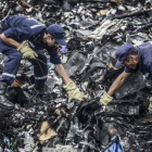 Dos agentes buscan entre los restos del vuelo MH17 de Malaysia Airlines, el pasado 20 de julio en Donetsk (Ucrania).-Foto: AFP / BULENT KILIC