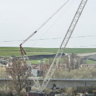 Una grúa de grandes dimensiones ha empezado a descolgar vías, barandillas y otros elementos del puente.-ISRAEL L. MURILLO