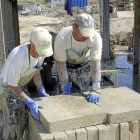 Dos operarios mueven placas de piedra en Villamayor-Ical