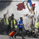 Un hombre pasa junto a un mural que reproduce una versión de La libertad guiando al pueblo, de  Eugene Delacroix, con la presencia de chalecos amarillos, idea del artista Pascal Boyart.-GETTY IMAGES