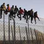 Policías españoles tratan de disuadir a inmigrantes encaramados a la valla de Melilla, fronteriza con Marruecos. /-EFE / ARCHIVO