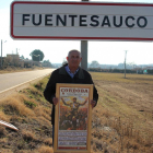 Amador Zamorano posa en la entrada de Fuentesauco con uno de los carteles de la muestra-E.M