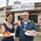 Alfonso y Alicia, con las patatas revolconas y una pieza de carne, a la entrada del establecimiento.-ARGICOMUNICACIÓN