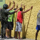 Policías militares cachean a sospechosos en Vila Velha, en el estado de Espirito Santo.-PAULO WHITAKER / REUTERS
