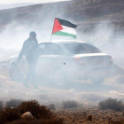 Un hombre ondea la bandera palestina entre gas lacrimogeno en el pueblo cisjordano de Shiyoukh.-ABED AL HASHLAMOUN (EFE)
