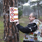 Un motero muestra un cartel en el que se prohíbe acampar, los vehículos a motor y encender hogueras en el Pinar de Puenteduero-J.M.Lostau