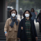 Dos mujeres con mascarilla caminan por la calle en Pekín (China).-EFE