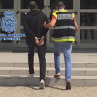 Un agente de la policía se lleva detenido al sospechoso.-ICAL