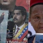Una partidaria del chavismo llora mientras sostiene imágenes de Chávez y Maduro, durante una marcha por el quinto aniversario de la muerte de Chávez, en Caracas, el 15 de marzo.-AP / FERNANDO LLANO