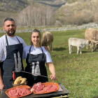 Aída y David frente a terneras de raza parda de su explotación con algunas de las piezas de carne que comercializan online y sirven en su restaurante. / E.M.