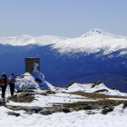 Un grupo de montañeros alcanza la cumbre del pico nevero, con el pico Peñalara al fondo.-N.S.