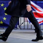 Un hombre camina junto a una bandera de la UE y otra del Reino Unido, en Londres.-TOLGA AKMEN (AFP)