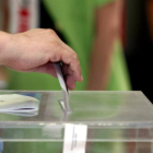 El presidente de una mesa electoral de Valladolid introduce en la urna el voto de un ciudadano.-ICAL