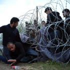 Refugiados sirios cruzan la alambrada de espino situada por las autoridades húngaras en su frontera.-Bela Szandelszky/AP/BEA SZANDELSKY