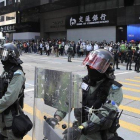 Policía antidisturbios vigila a manifestantes en el distrito financiero de Hong Kong.-KIN CHEUNG (AP)