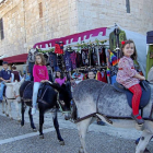 Los niños pasean en burro por delante de los puestos del mercado de oficios.-D. V.