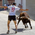 Un joven esquiva a uno de los toros del encierro ante la mirada del público en Pollos.-PABLO REQUEJO / PHOTOGENIC