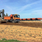 Una pala excavadora y un camión trabajan ayer en el movimiento de terrenos sobre la parcela de la ampliación, junto a la bodega Protos (al fondo).-EL MUNDO