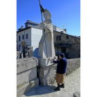 Una mujer toca la estatua de un peregrino del Camino de Santiago que hace de parada para los caminantes  en el pueblo leonés de Villafranca del Bierzo.-EL MUNDO