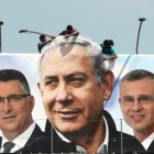 Un grupo de operarios trabaja en una valla publicitaria de propaganda electoral en la que aparece Netanyahu con candidatos de su partido, el Likud, en Jerusalén.-REUTERS / AMMAR AWAD