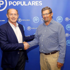 Luis Minguela y José Mongil se dan la mano ayer, en la asamblea del PP.-J.M.LOSTAU