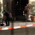 Un agente examina la mochila en la que el autor del ataque llevaba los explosivos, frente a un restaurante de Ansbach (Alemania), este domingo.-AP / MATTHIAS SCHRADER