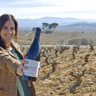 Adriana Ulibarri, con uno de los tintos de la bodega, en el lugar donde se emplazará la futura bodega, en las laderas de Valtuille de Arriba.-ARGICOMUNICACIÓN