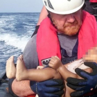 Un miembrod de la oenegé Sea Watch sostiene el cadáver de un bebé muerto recuperado de las aguas del Mediterráneo entre Libia e Italia.-CHRISTIAN BUETTNER