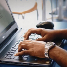 Un hombre escribe en un ordenador portátil.-
