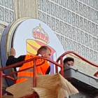 Dos operarios colocan el escudo nuevo en la fachada del club.