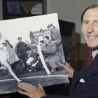 Roger Bannister, en una imagen de 1974, mostrando una foto de 20 años antes batiendo el récord de la milla.-AFP