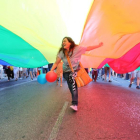 Una joven corre por debajo de la bandera arcoíris en una manifestación LGTBI.-EL MUNDO