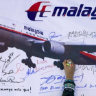 Una mujer escribe un mensaje de solidaridad con los pasajeros del vuelo desaparecido de Malaysia Airlines en Kuala Lumpur en el 2014.-/ SAMSUL SAID (REUTERS)