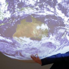 Un participante en la cumbre del clima posa ante la bola del mundo que se exhibe en el encuentro-REUTERS / STEPHANE MAHE