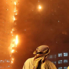 Dos oficiales emiratíes miran como se estiende el fuego a lo largo del edificio.-Kamran Jebreili