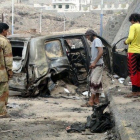 Varias personas contemplan los efectos del atentado con coche bomba en el que ha muerto el gobernador de Aden.-REUTERS