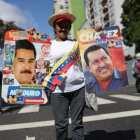 Una simpatizante de Maduro sostiene un cartel del mandatario y otro de Hugo Chávez  en una manifestación en Caracas.-RODRIGO ABD (AP)