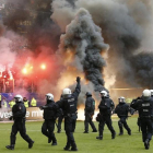 Antidisturbios saltan al césped del estadio del Hamburgo mientras en la grada se queman camisetas y banderas.-AP / MICHAEL SOHN