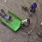 Lecheros intentan abrirse paso por una calle inundada tras las fuertes lluvias en Allahabad, India.  /-RAJESH KUMAR SINGH (AP)