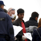 Un funcionario de la UE sostiene la documentación de un migrante (centro) en un barco que les traslada de regreso a Turquía desde Lesbos, este viernes.-REUTERS / GIORGOS MOUTAFIS