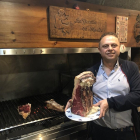 Fernando, en su restaurante, junto a una de sus afamadas piezas de carne rojas de buey, su especialidad-