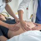 Una mujer embarazada junto a una enfermera y una médico en una revisión-E. M.