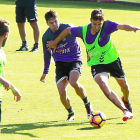 Mata conduce el balón mientras aparta con la mano a Markel, durante un entrenamiento.-J.M.LOSTAU